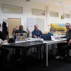 The crew of HWC Nuremberg 12/2024. 4 people with laptops sitting around a table.