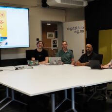 Four people sit at a conference table in a modern meeting room called "digital lab wg.110," with laptops and a large screen displaying the cover of "Das Web-Adressbuch für Deutschland 2019."